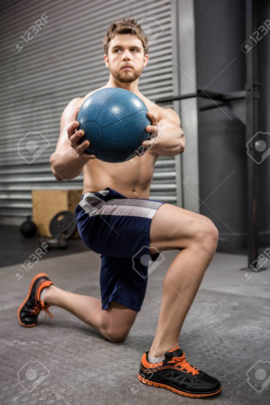 shirtless man training with medicine ball at the crossfit gym stock
