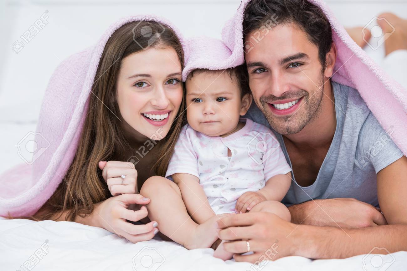 Portrait De Couple Souriant Avec Bebe Sur Le Lit A La Maison Banque D Images Et Photos Libres De Droits Image