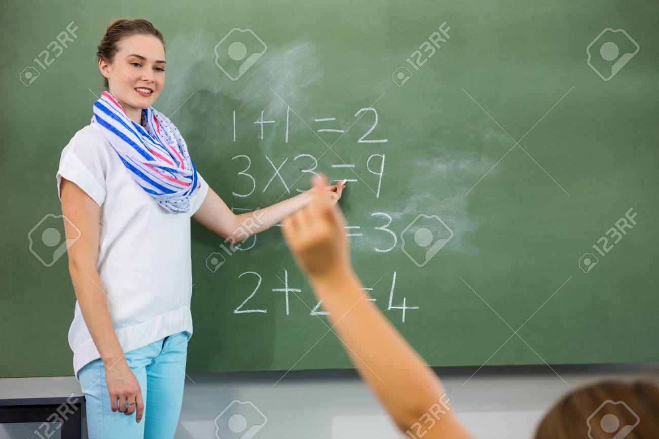 teacher teaching mathematics on chalkboard in classroom stock photo