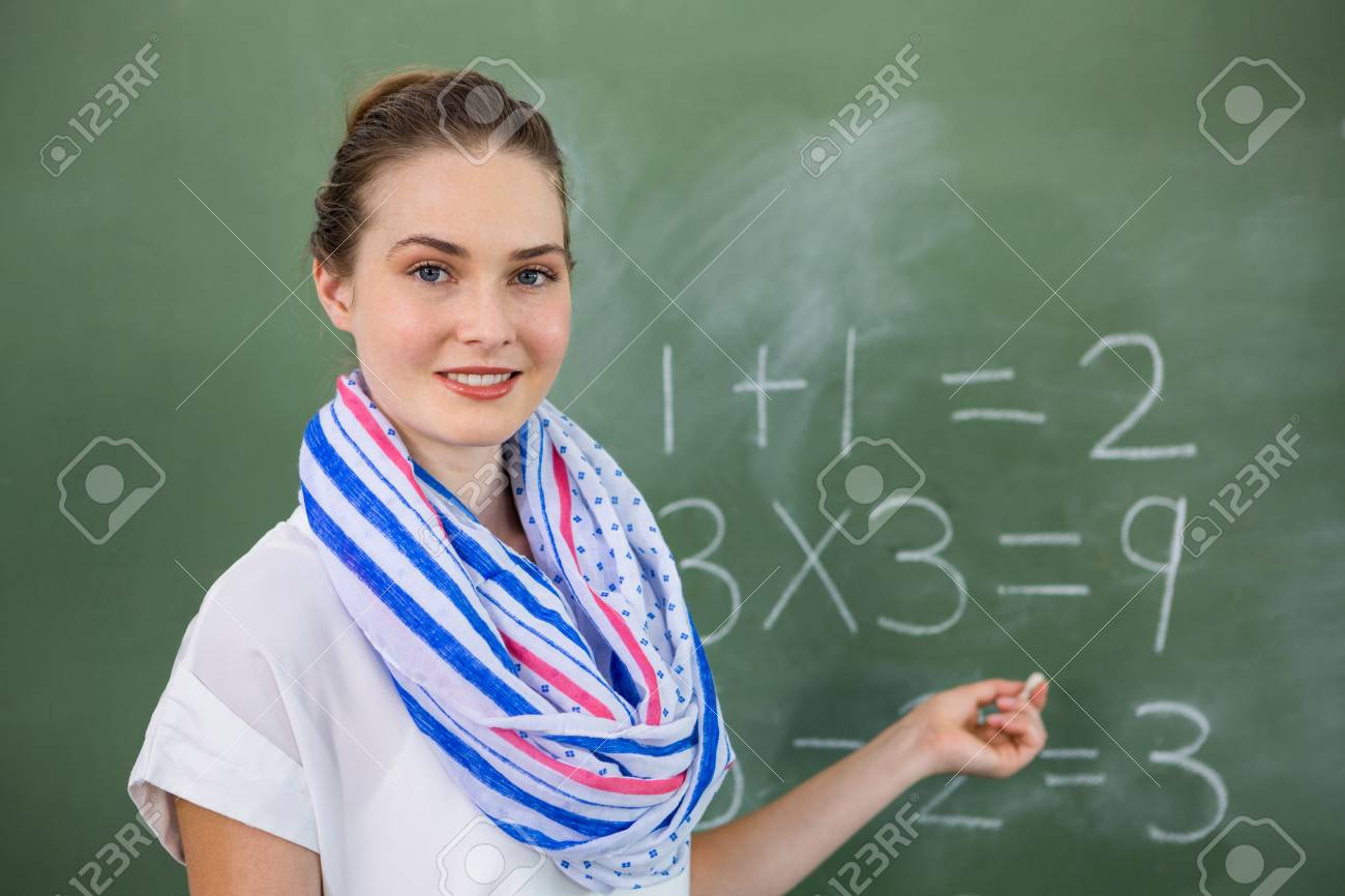 portrait of young teacher teaching mathematics on chalkboard stock