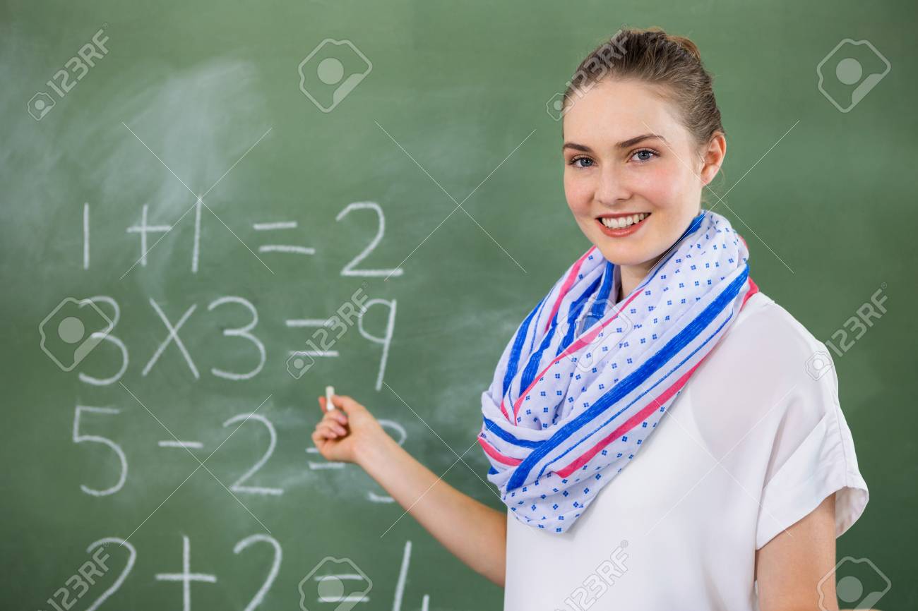 portrait of teacher teaching mathematics on chalkboard in classroom