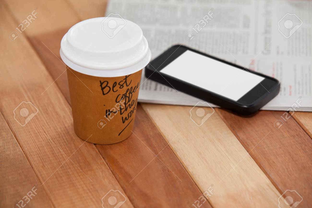 使い捨てのコーヒー カップ 携帯電話と木製の背景に新聞のクローズ アップ の写真素材 画像素材 Image
