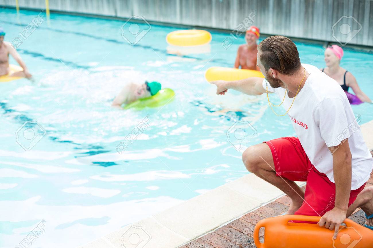Male lifeguard assisting swimmers at poolside - 75351242 Male lifeguard assisting swimmers at poolside - 75351242
