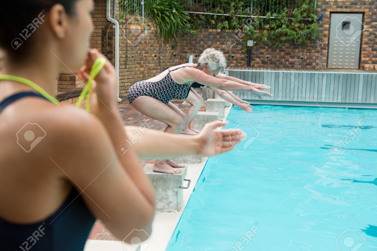 シニア女性のレジャー センターでプールに飛び込む間笛を吹く女性トレーナー の写真素材 画像素材 Image