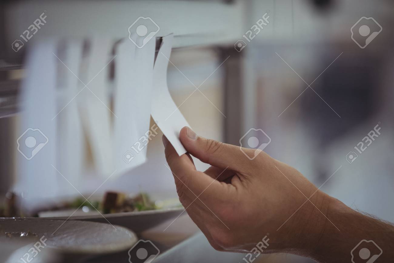 Close Up Of Chef Holding An Order List In The Commercial Kitchen