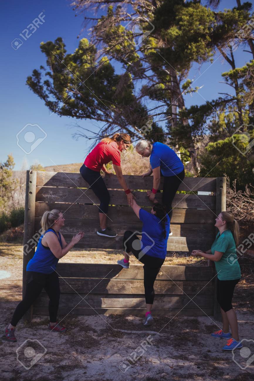 Mujer Que Es Ayudada Por Sus Companeros De Equipo Para Subir Una