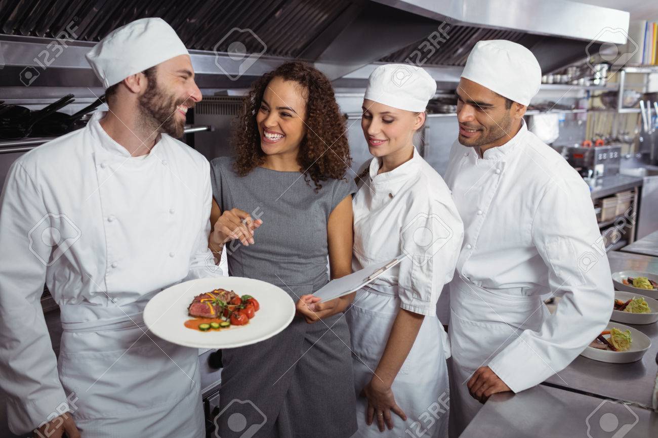 restaurant manager interacting with his kitchen staff in commercial kitchen staff