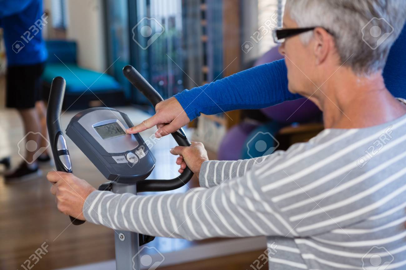 physiotherapist showing workout record on exercise bike in clinic workout record