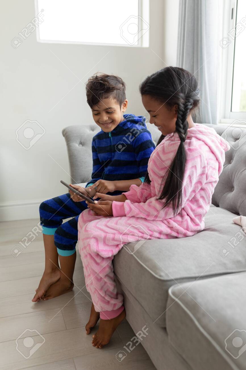 Side view of African american Happy Siblings using digital tablet on a sofa in living room at home - 126117917 Side view of African american Happy Siblings using digital tablet on a sofa in living room at home - 126117917