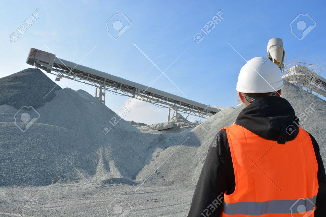 Worker and heavy machine for gravel production in background - 40258605 Worker and heavy machine for gravel production in background - 40258605