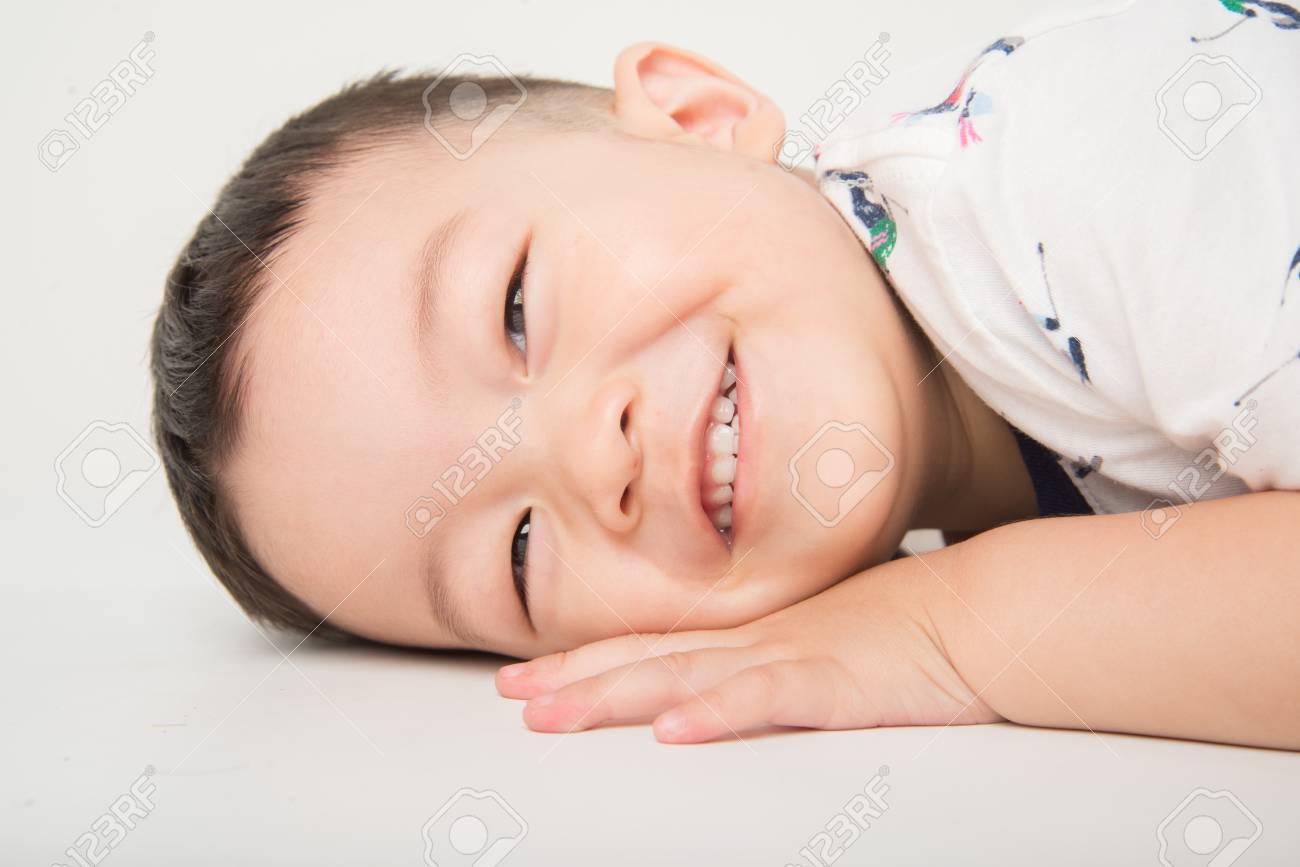 Happy Boy Toddler Lay Down On The Floor With Smile Face On White