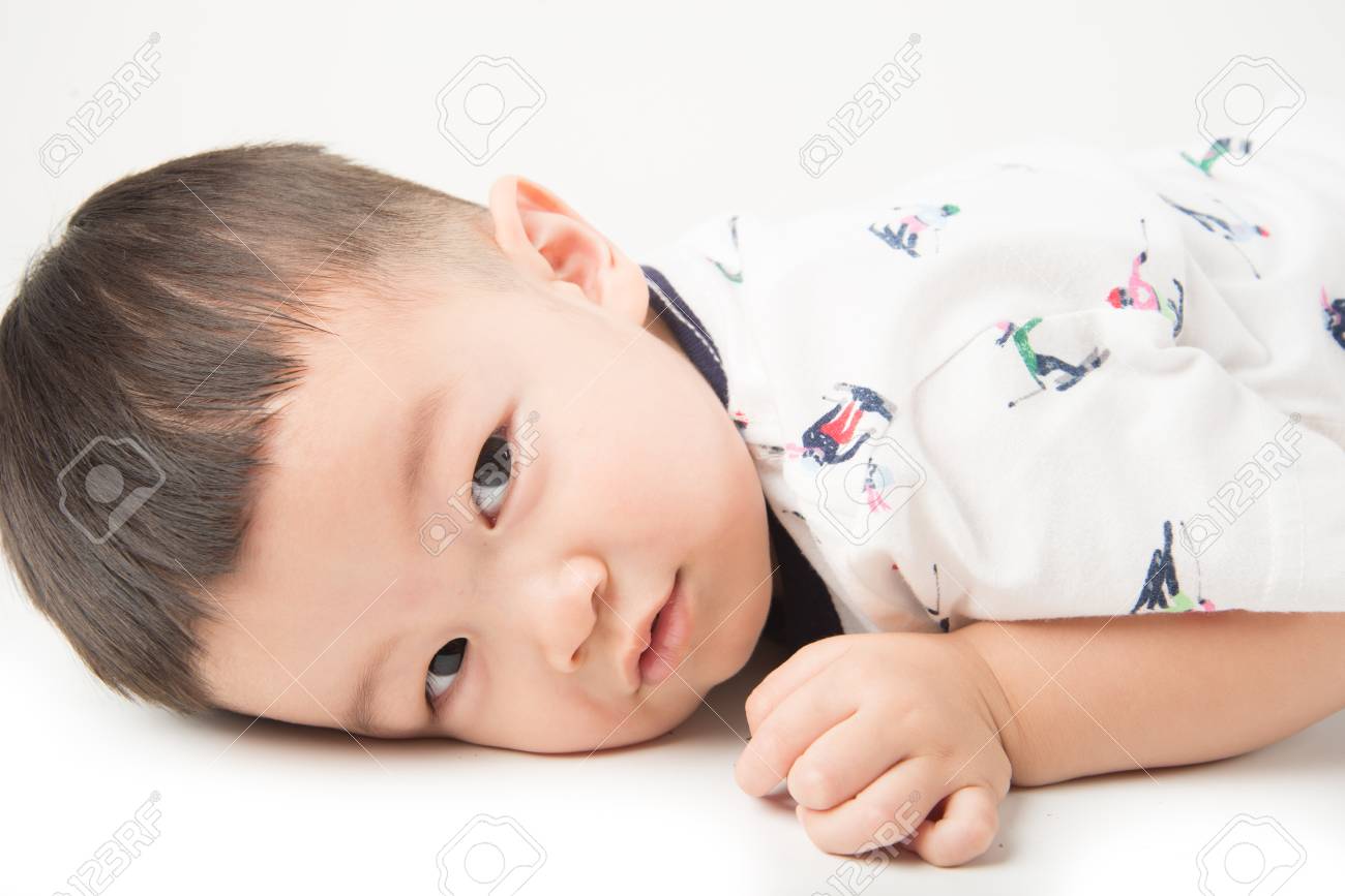 Happy Boy Toddler Lay Down On The Floor With Smile Face On White
