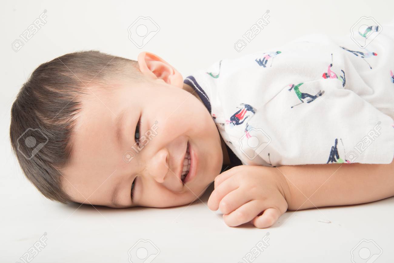 Happy Boy Toddler Lay Down On The Floor With Smile Face On White