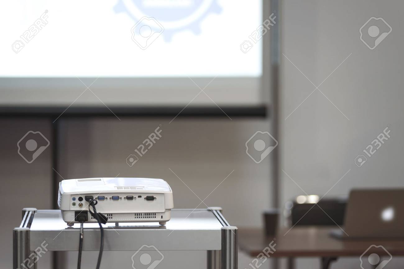 White multimedia projector in a conference room with blured projection screen and a lecturer desk on the background (reduced tone) - 73046891 White multimedia projector in a conference room with blured projection screen and a lecturer desk on the background (reduced tone) - 73046891