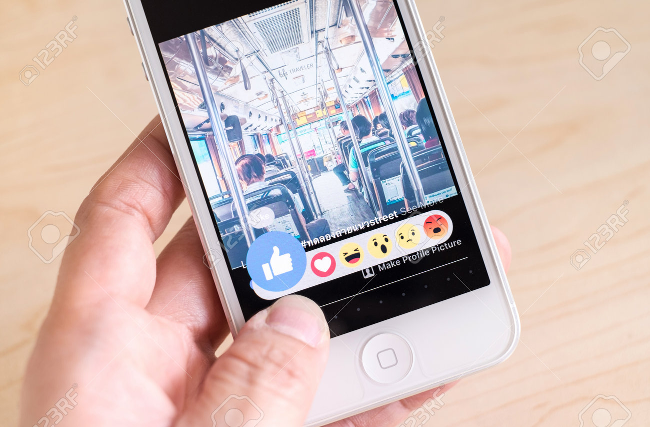 バンコク タイ王国 16 年 2 月 26 日 画面のボタン 6 絵文字 のような新しい Facebook の Iphone を持っている手 ソーシャル メディアを使用している情報の共有とネットワー キングの の写真素材 画像素材 Image