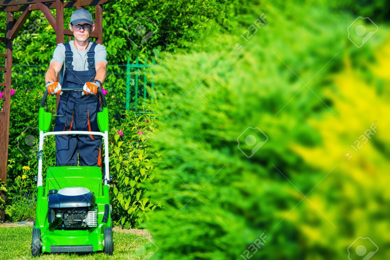 caucasian gardener mowing the grass using professional grass stock works garden equipment