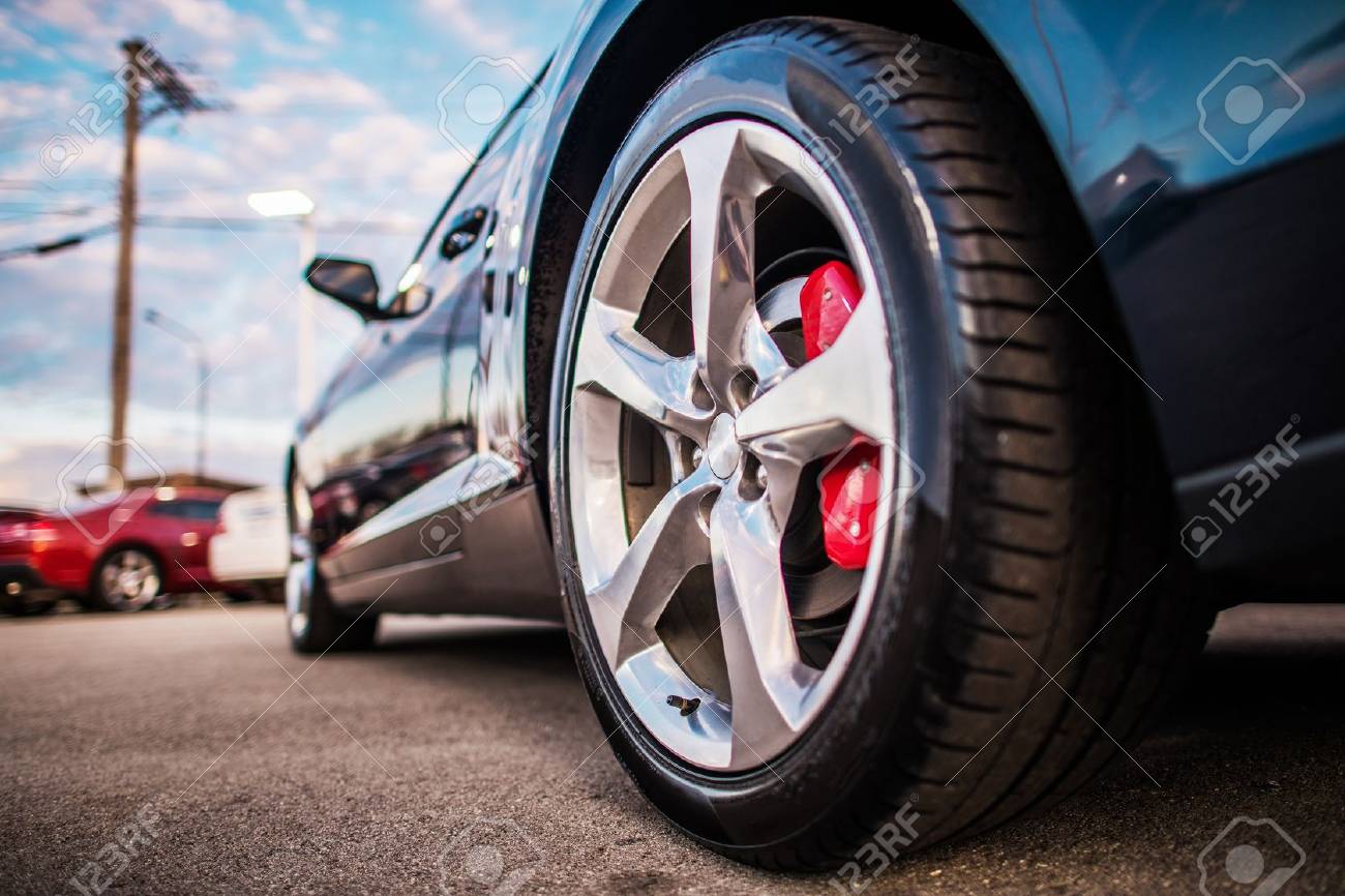 https://previews.123rf.com/images/welcomia/welcomia1803/welcomia180300099/98930867-car-on-the-parking-spot-alloy-wheel-closeup-photo-lower-ground-level-transportation-and.jpg