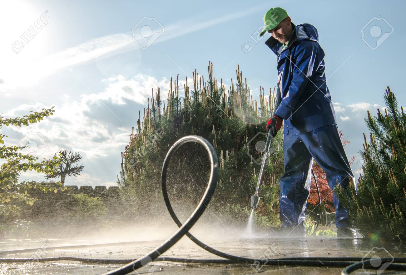 Garden Washing Maintenance. Caucasian Worker in His 30s with Pressure Washer Cleaning Brick Paths. - 122097833 Garden Washing Maintenance. Caucasian Worker in His 30s with Pressure Washer Cleaning Brick Paths. - 122097833