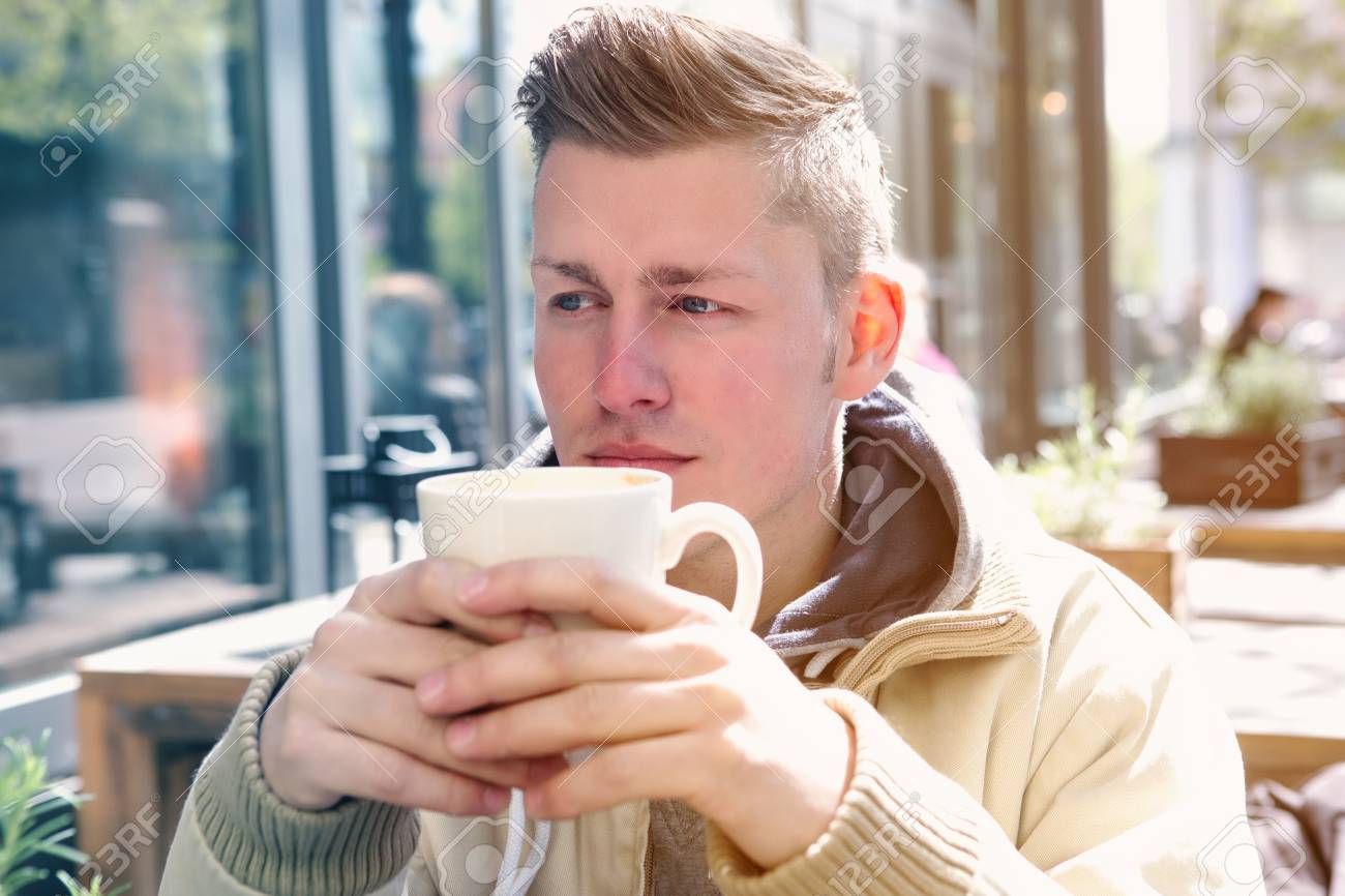 金髪の若い男外に座っていると コップから飲む の写真素材 画像素材 Image