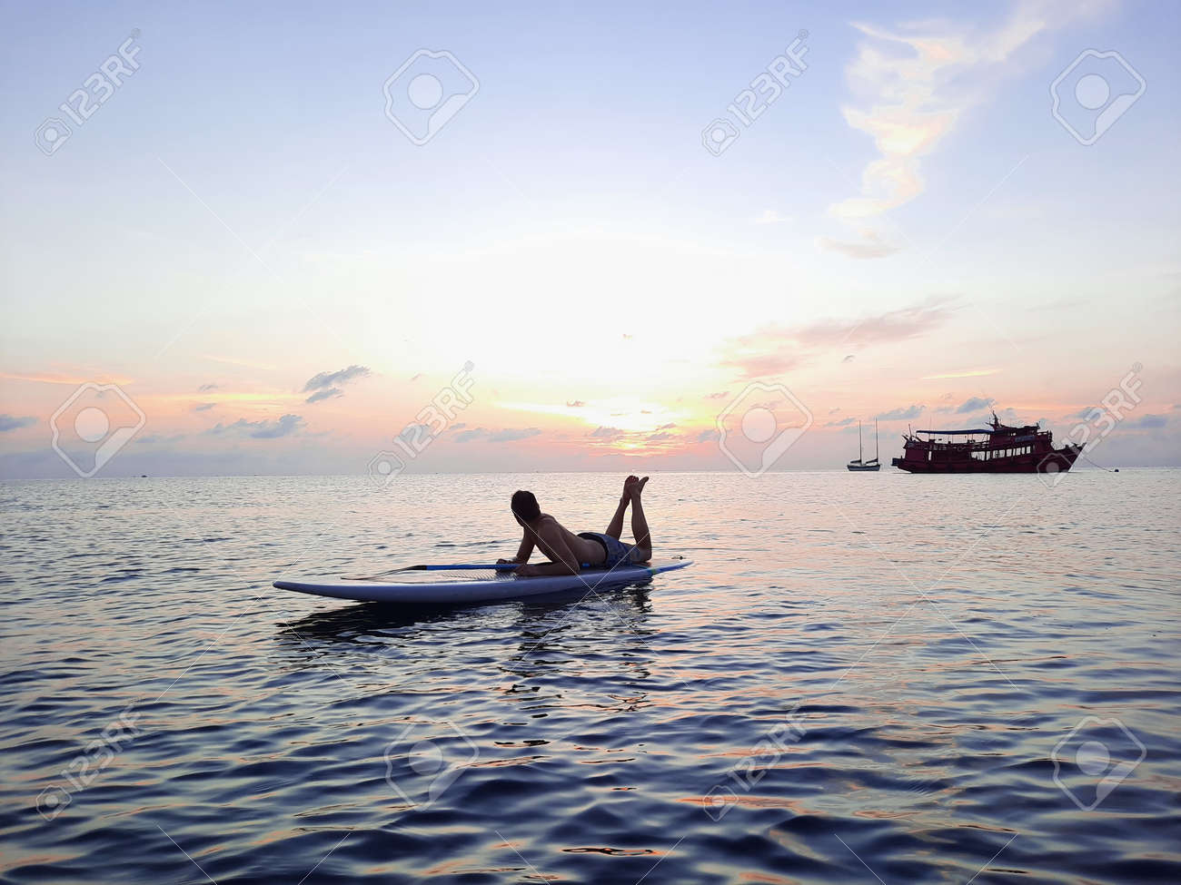 on a stand up paddle board, young man 34 years old, German, lies on a board on the ocean in Thailand, on the island Koh Tao at sunset - 169664543 on a stand up paddle board, young man 34 years old, German, lies on a board on the ocean in Thailand, on the island Koh Tao at sunset - 169664543