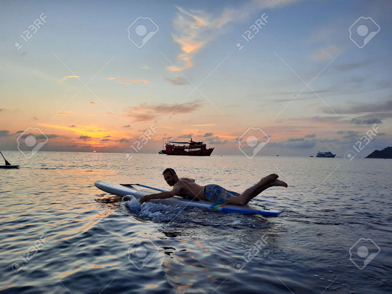 on a stand up paddle board, young man 34 years old, German, lies on a board on the ocean in Thailand, on the island Koh Tao at sunset - 169664552 on a stand up paddle board, young man 34 years old, German, lies on a board on the ocean in Thailand, on the island Koh Tao at sunset - 169664552