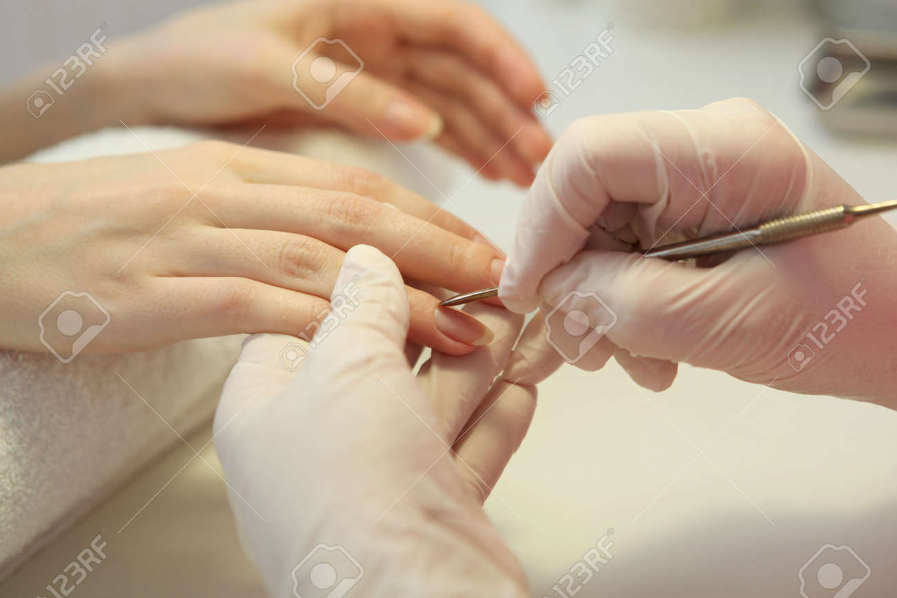 Closeup shot of a woman in a nail salon getting a manicure by a cosmetologist with a nail file. Woman gets a manicure of nails. Beautician puts nails on the client. High quality photo - 168564559 Closeup shot of a woman in a nail salon getting a manicure by a cosmetologist with a nail file. Woman gets a manicure of nails. Beautician puts nails on the client. High quality photo - 168564559