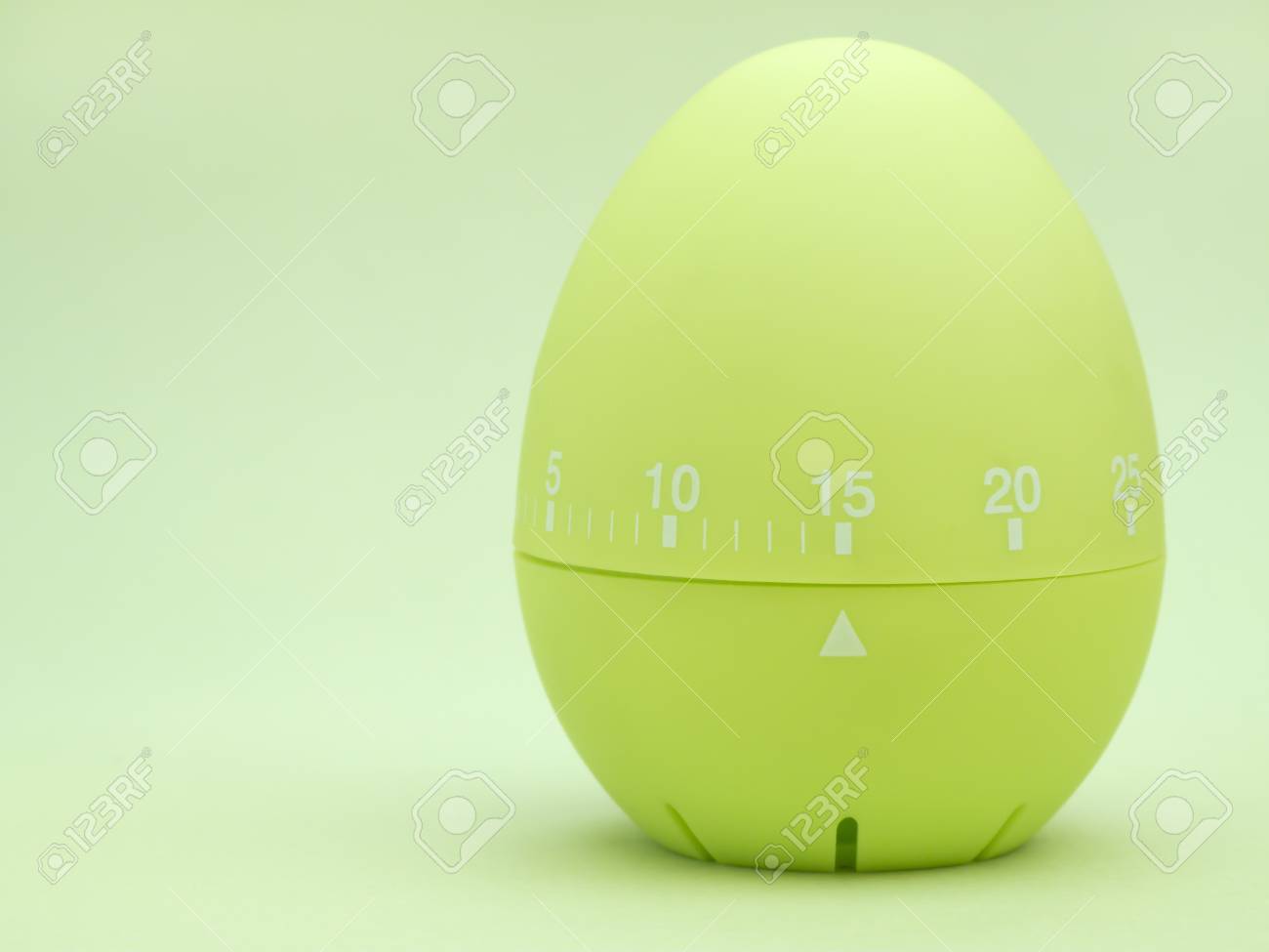 green egg shaped kitchen timer set to 15 minutes on green background