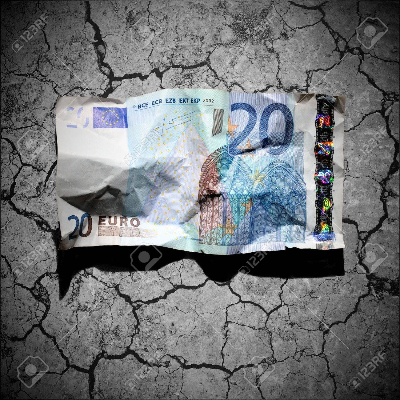 Financial crisis concept - crumpled 20 euro banknote on dry soil background - 12748595 Financial crisis concept - crumpled 20 euro banknote on dry soil background - 12748595