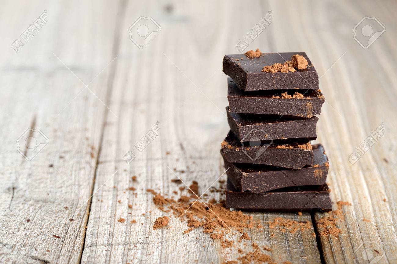 Pile of chocolate pieces with cocoa on wooden background - 27433373 Pile of chocolate pieces with cocoa on wooden background - 27433373