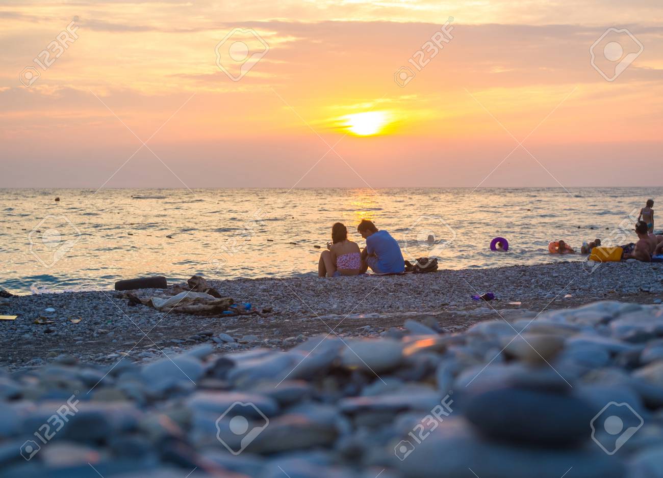 Un Couple Et Des Pierres De Galets Zen Pliés Pyramide Sur La Plage De La Mer Au Coucher Du Soleil