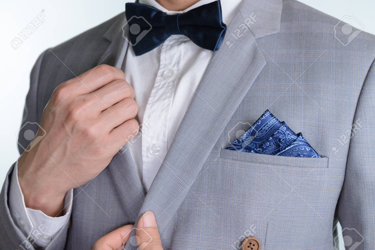 Man in grey suit, plaid texture, blue bowtie and pocket square,..