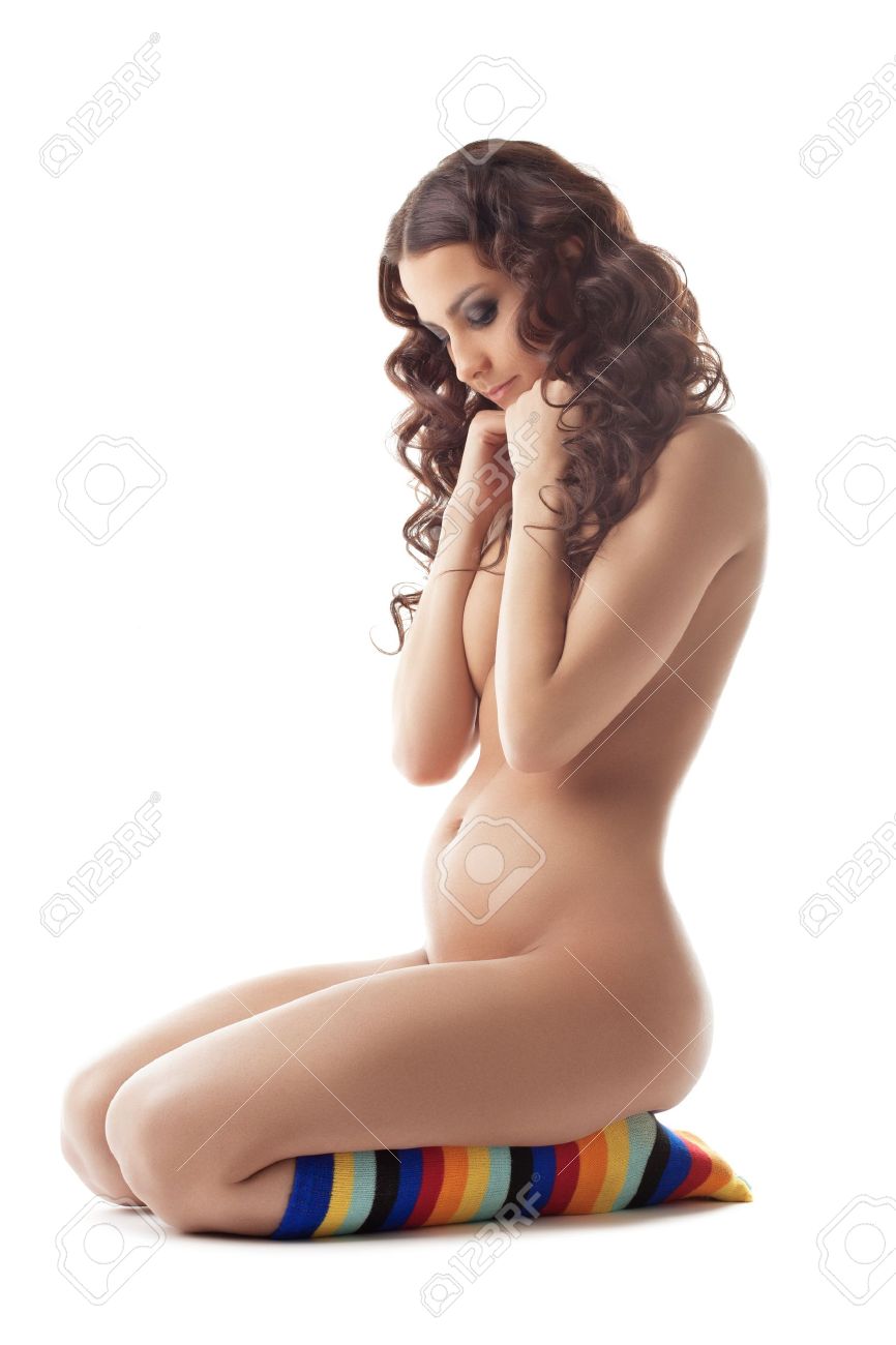 Young sexy nude pregnant woman sit in color socks look at breast..