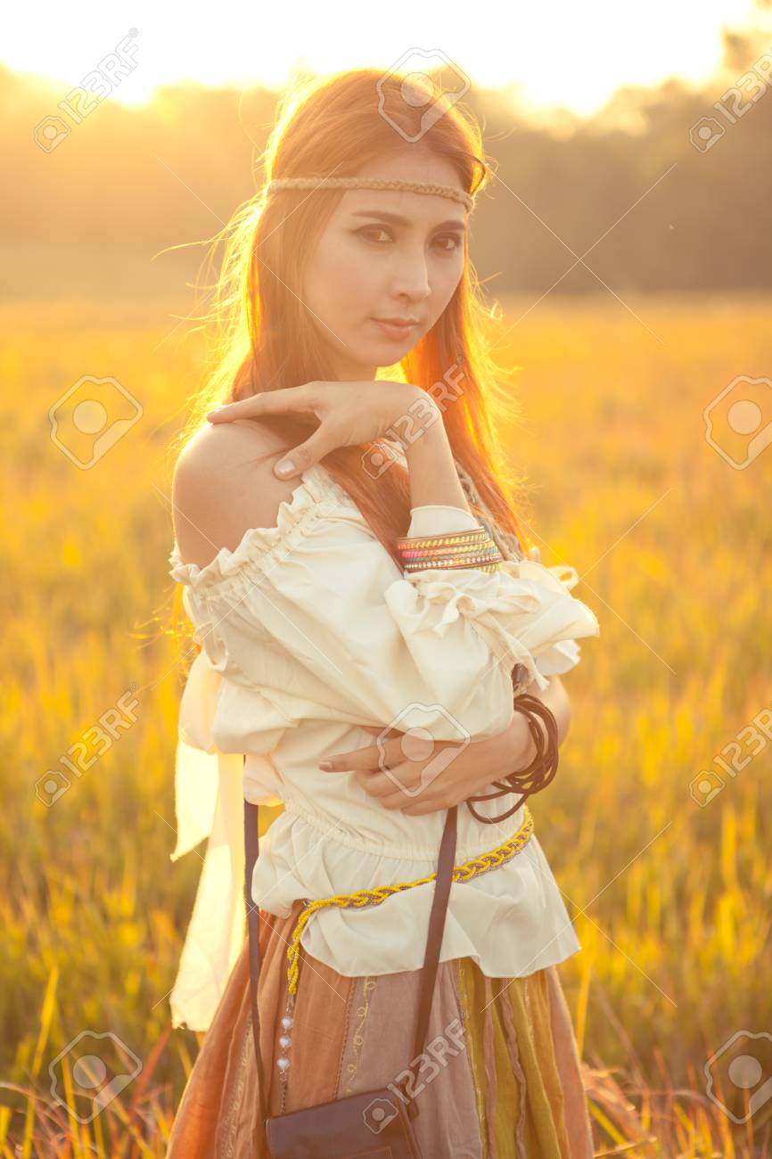 ヒッピー女性が夕日で黄金フィールドでポーズ の写真素材 画像素材 Image