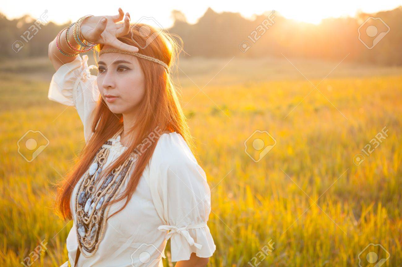 ヒッピー女性が夕日で黄金フィールドでポーズ の写真素材 画像素材 Image