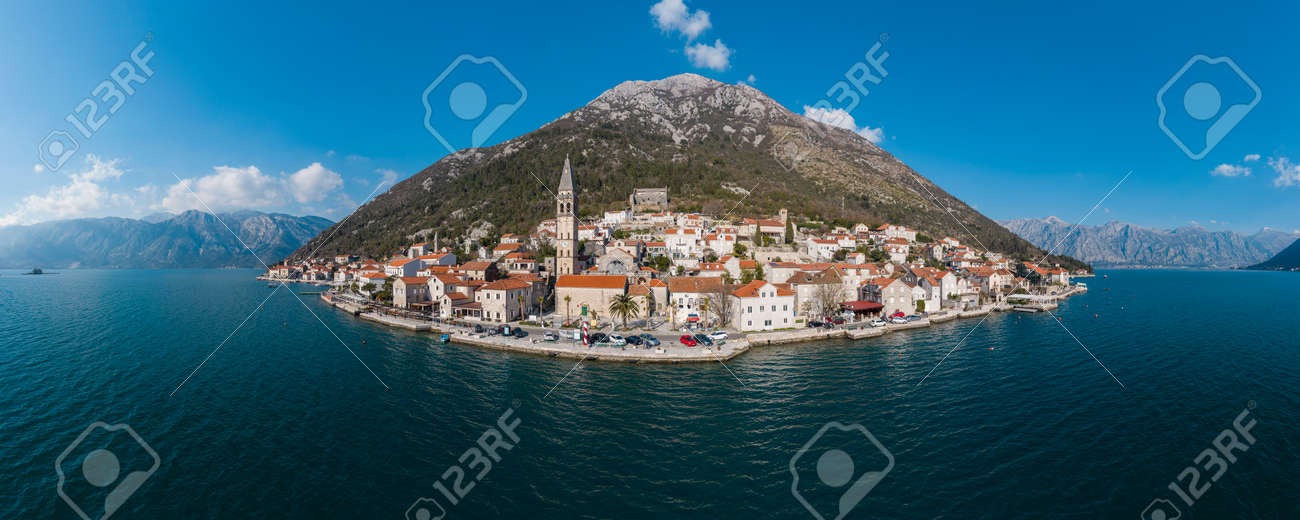 Panorama bird's eye view of small island in Adriatic sea, covered by greenery, traditional Balkan style architecture, ancient buildings and cathedral. Mountains in the background - 166666245 Panorama bird's eye view of small island in Adriatic sea, covered by greenery, traditional Balkan style architecture, ancient buildings and cathedral. Mountains in the background - 166666245
