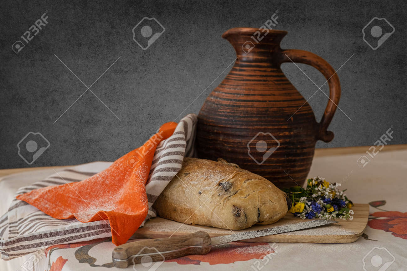 Still life, food photography - close-up of fresh sliced white bread on a cutting board on the table, knife, linen towel and little bouquet of wildflowers, a jug of milk in the background - 170377733 Still life, food photography - close-up of fresh sliced white bread on a cutting board on the table, knife, linen towel and little bouquet of wildflowers, a jug of milk in the background - 170377733