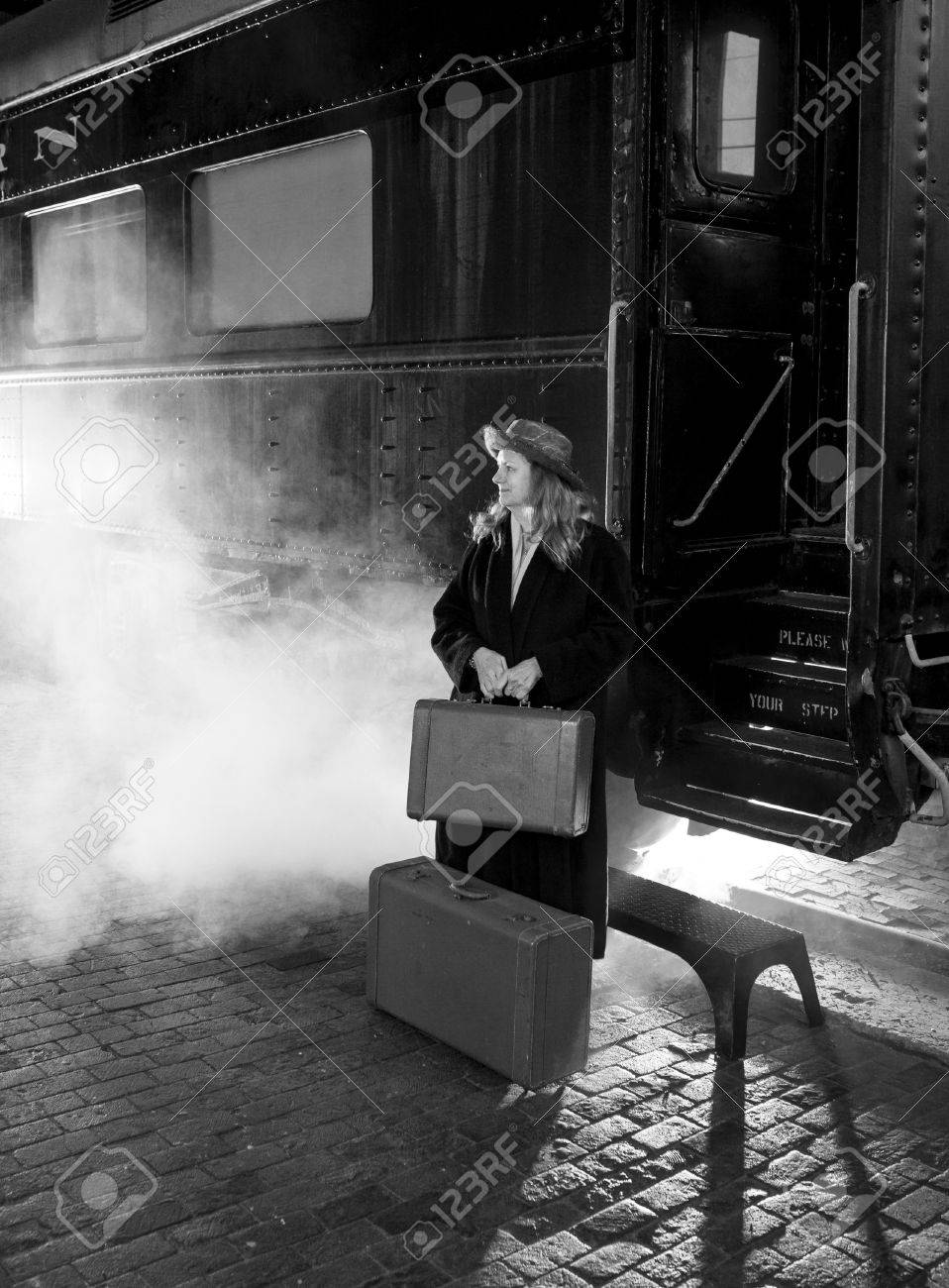 Stock photo woman in 1950s clothing leaving on steam train black and white