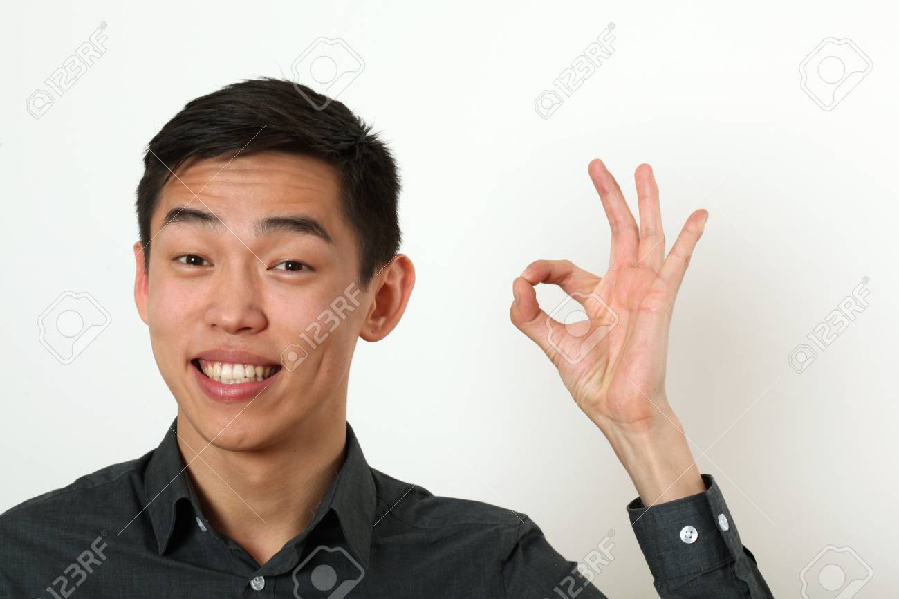 若いアジア人大丈夫のサインを与えることと カメラを見てにこにこしています の写真素材 画像素材 Image
