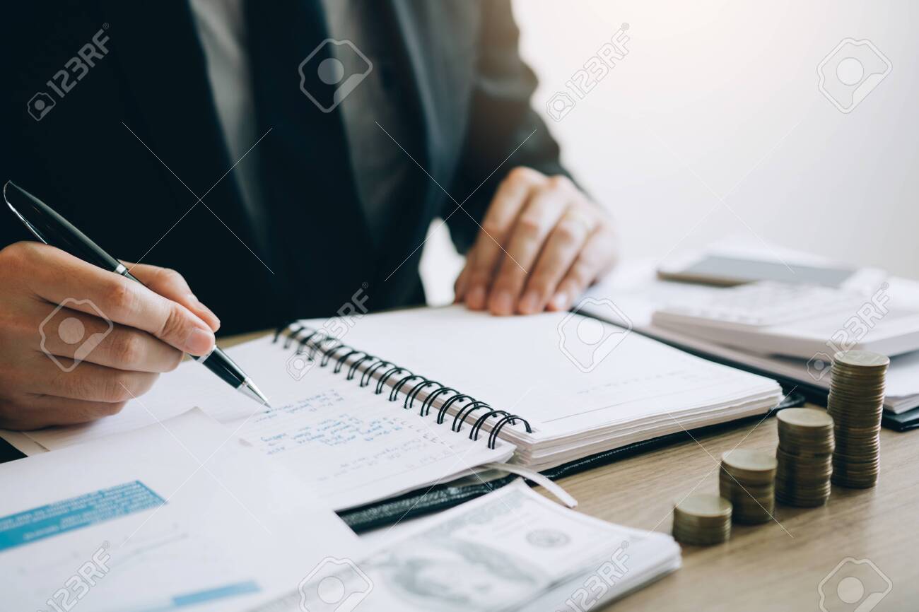 Businessmen are calculating the cost of the company's sales and analyzing the graph in the office. - 120428389 Businessmen are calculating the cost of the company's sales and analyzing the graph in the office. - 120428389