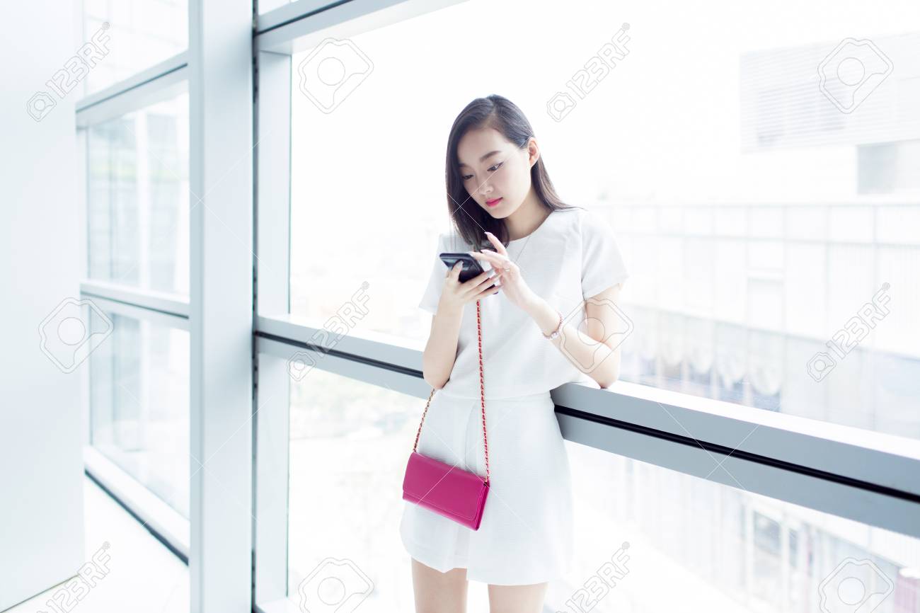 中国の若い女の子がショッピング モールで彼女の電話で遊んで の写真素材 画像素材 Image