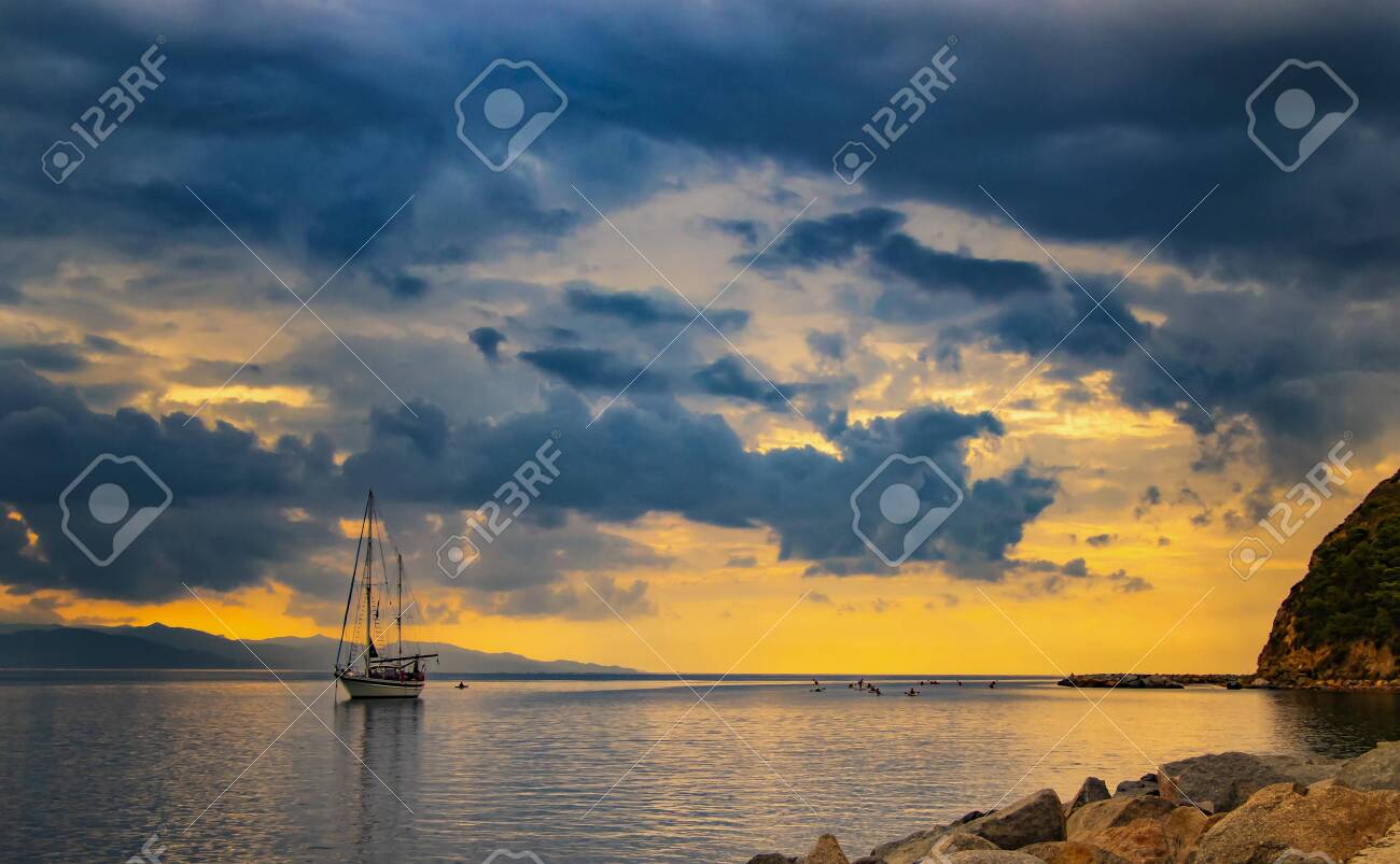 Yacht In The Mediterranean Sea At Sunrise Cagliari Italy People Sail On Kayaks On The Open