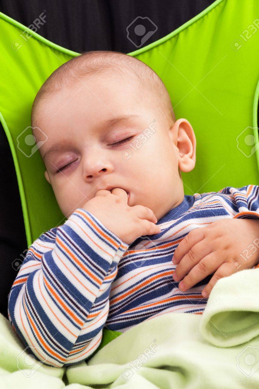 彼の指をしゃぶり赤ちゃんラウンジャーで寝ているかわいい幼児少年 の