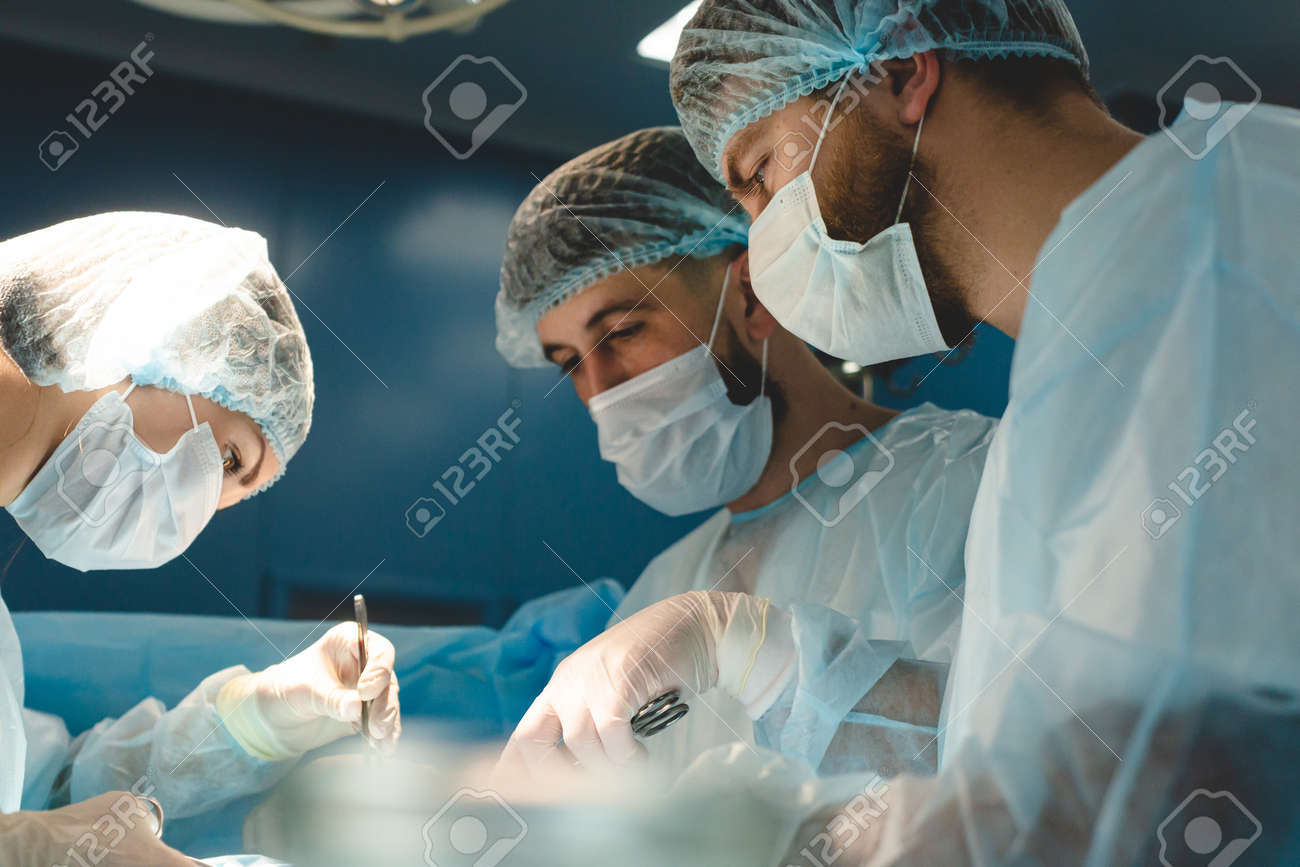 An international team of doctors performs a complex surgical operation on a patient under anesthesia. Modern operating room and experienced surgeons save lives - 171614704 An international team of doctors performs a complex surgical operation on a patient under anesthesia. Modern operating room and experienced surgeons save lives - 171614704