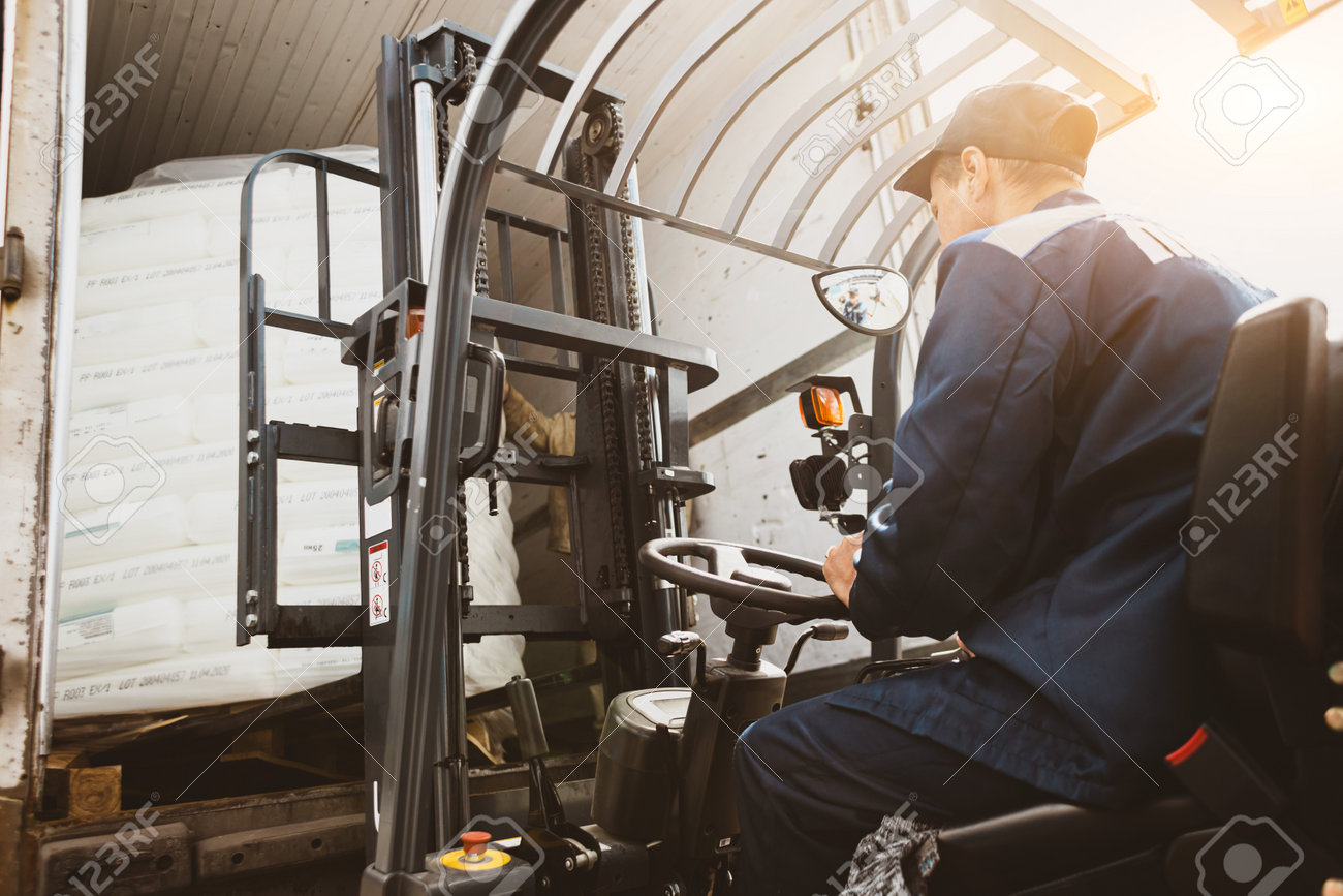 A man on a forklift works in a large warehouse, unloads bags of raw materials - 171983157 A man on a forklift works in a large warehouse, unloads bags of raw materials - 171983157