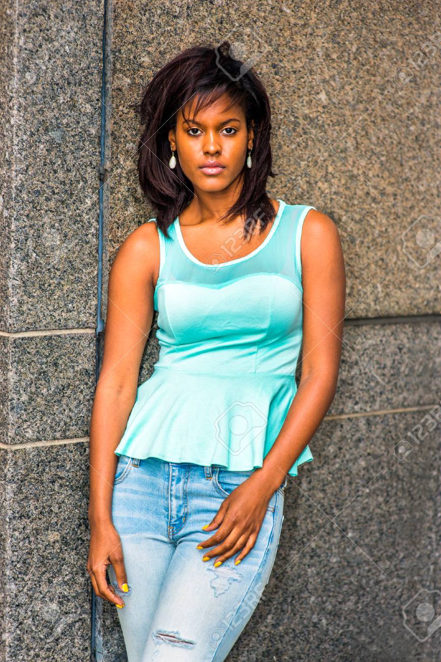 孤独な少女 緑のタンクトップ おしゃれなジーンズ イヤリングを着て ニューヨーク 悲しいで壁に立っている若いアフリカ系アメリカ人の女性は考えて 思案に暮れています の写真素材 画像素材 Image