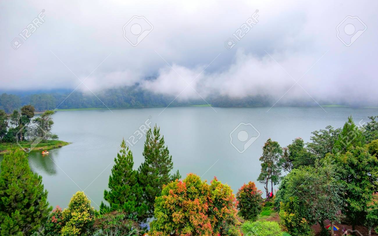 Die Schone Landschaft Des Riesigen Sees Mit Baumen Und Nebel Schafft Eine Beruhigende Atmosphare In Der Mitte Des Sees Gibt Es Auch Ein Kleines Boot Das Den See Erforscht Lizenzfreie Fotos Bilder