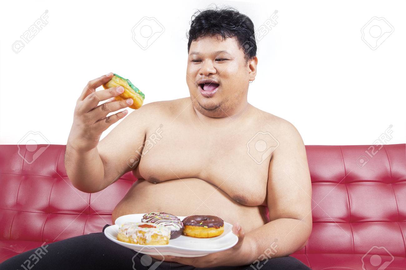 陽気なデブ男自宅のソファに座りながらドーナツを見て の写真素材 画像素材 Image