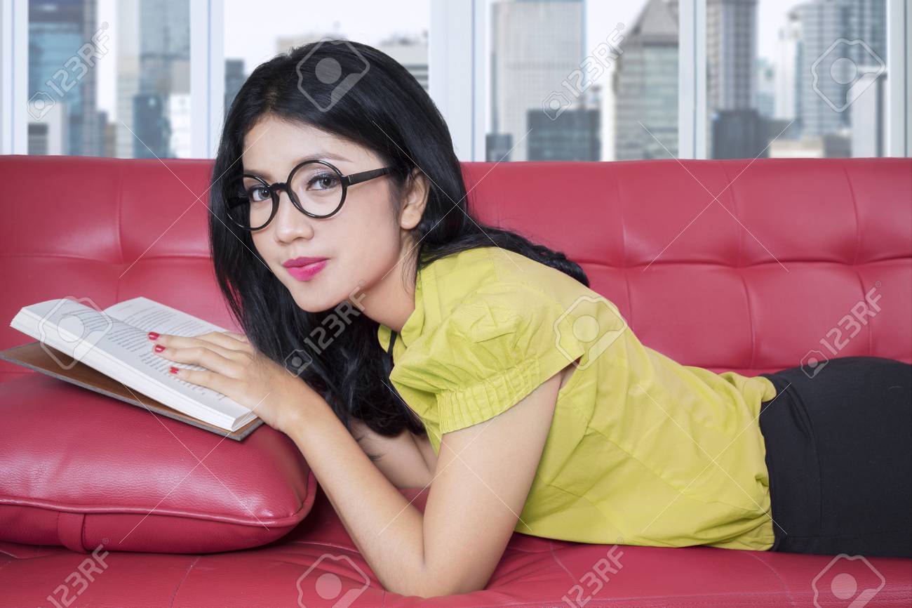 ソファの上に横たわっている間本を読んで長い髪と眼鏡をかけて 素敵な女性 の写真素材 画像素材 Image