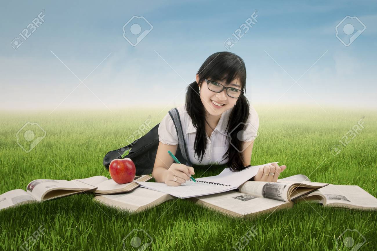 勉強し カメラに笑顔ながら牧草地で横になっている魅力的な中国女子高生の写真 の写真素材 画像素材 Image