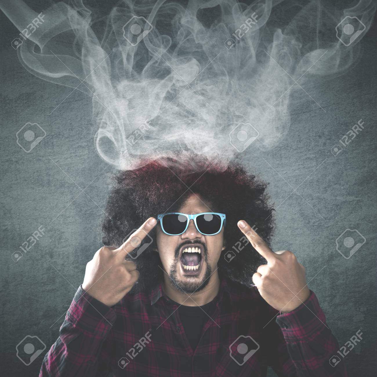 身に着けているサングラスと彼の頭から出てくる煙と 2 つの中指を見せながら怒りに見える毛 アフロ男の写真 の写真素材 画像素材 Image